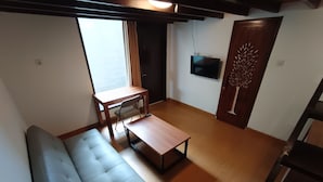 Ein Wohnzimmer mit einer Couch, einem Couchtisch, einem an der Wand montierten Fernseher und einer Tür mit Baumdekor.