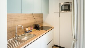 Een kleine keuken met een spoelbak, aanrecht, magnetron en een houten achterwand.
