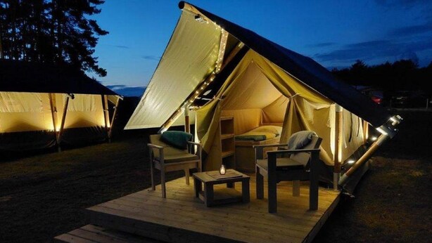 Une tente dotée d’une terrasse en bois, de chaises et d’une table.