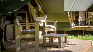 Une tente avec une table et des chaises en bois, un banc et une petite table.