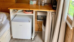 Una kitchenette compacta con refrigerador, un lavamanos pequeño y una encimera de madera.