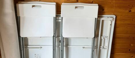 Two white appliances against a wooden wall, with a curtain partially visible on the left.