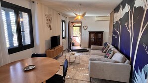 A living room with a sofa, a dining table, and a TV.