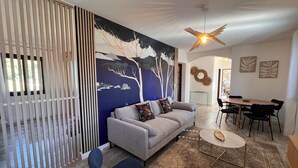 A modern living room with a sofa, a dining table, and a ceiling fan.