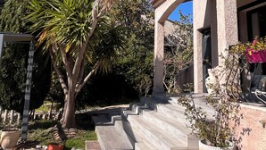 A building with a stucco exterior, a tiled roof, and a stone staircase leading to the entrance.