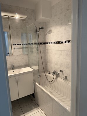 Ein modernes Badezimmer mit einer Glaskabine zur Dusche, einer freistehenden Badewanne und einem Waschtisch mit Spiegel.