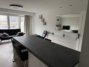 Eine moderne Küche mit dunkler Arbeitsplatte, weißen Schränken und einem großen Fenster mit Vorhängen.