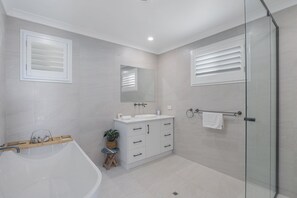 A modern bathroom with a bathtub, vanity, mirror, and glass shower enclosure. - White Haven | Spacious Coastal Luxury in the Heart of Point Lookout (point lookout)
