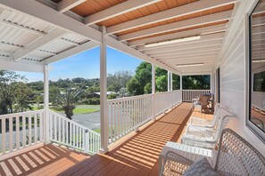 A covered porch with white railings, wooden flooring, and wicker furniture. - White Haven | Spacious Coastal Luxury in the Heart of Point Lookout (point lookout)