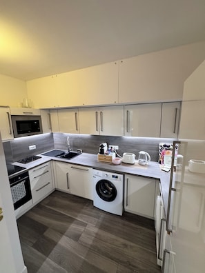A compact kitchen with a microwave, sink, stove, and a built-in washing machine. - Apartment Cannes Eden luxury residence (Vallauris)