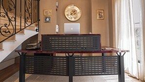 A reception desk with a laptop, a clock, and framed pictures on the wall. - Golden Boutique Hotel (Tbilisi)