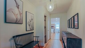 Een gang met een houten bank, een donker houten dressoir en lijstwerken aan de muren.