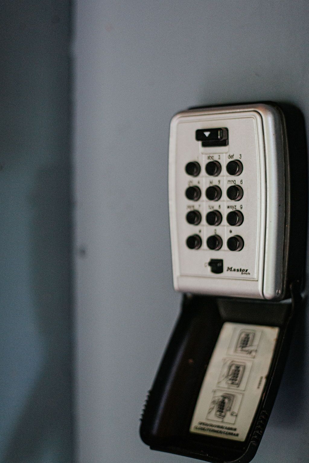 Un teléfono blanco con teclado y una pantalla pequeña, fijado a la pared.