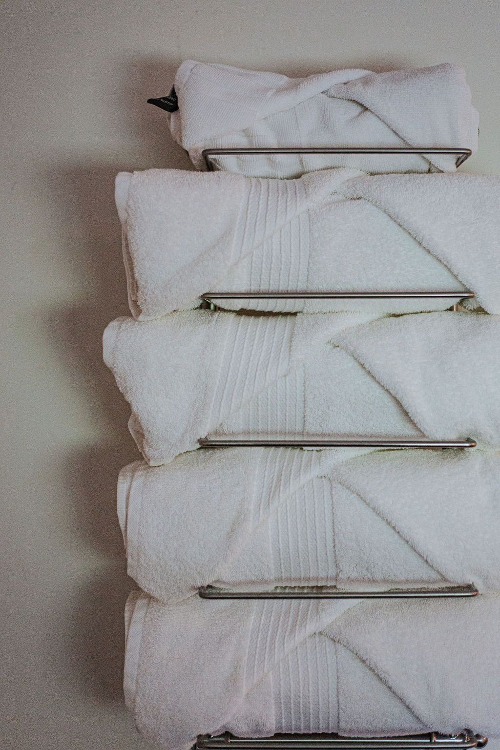 A stack of white towels with metal clips on a wall.