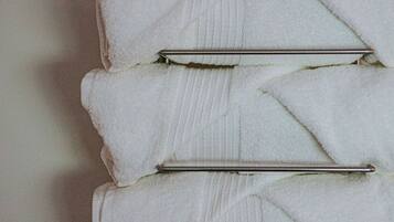 A stack of white towels with metal clips on a wall.