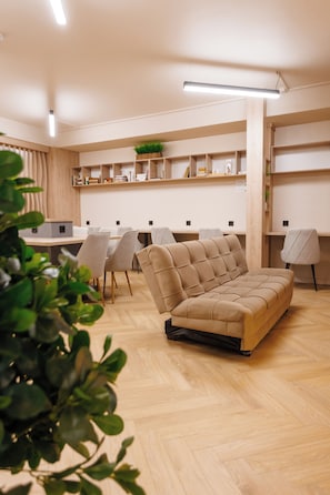 A modern interior with a sofa, chairs, a desk, shelves, and a plant.