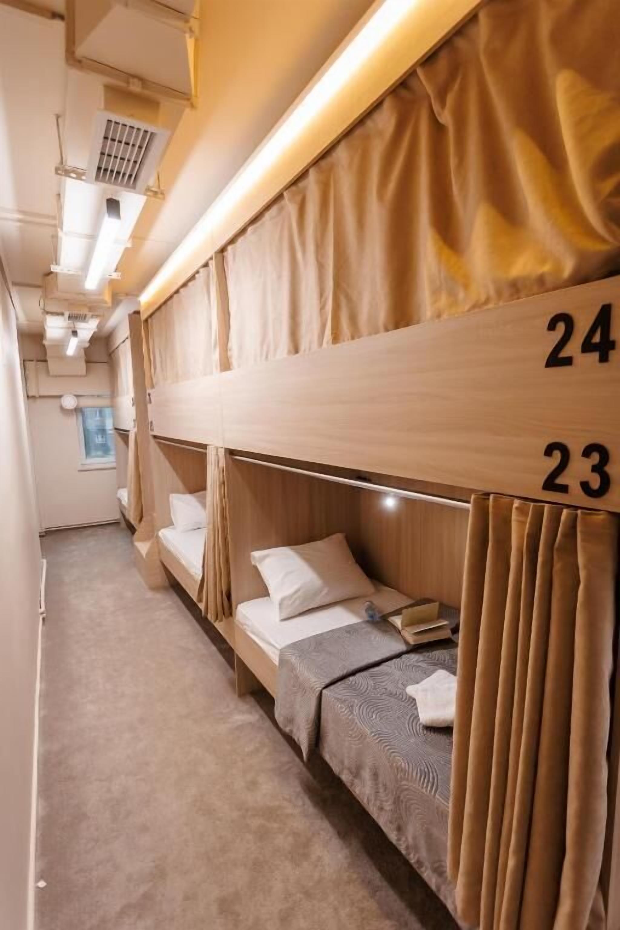A train compartment with bunk beds, numbered 23 and 24, and a window with curtains.