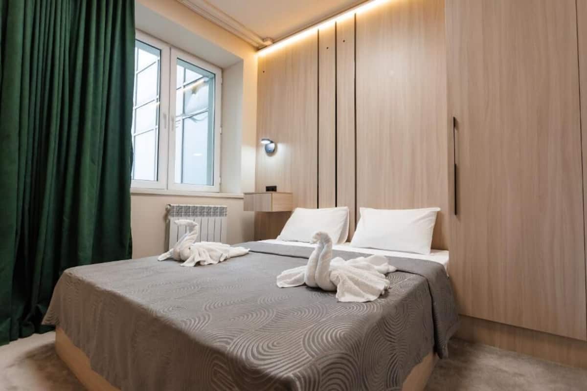 A hotel room with a bed, a window, a wall-mounted light, and a wardrobe.