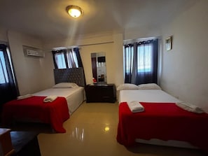 Una habitación de hotel con dos camas, un aparador, un aire acondicionado y un espejo.