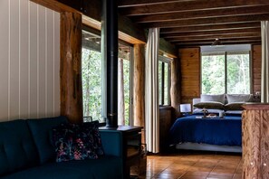 Una habitación acogedora con cama, sofá, ventanal grande y techo de madera.