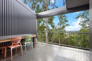 A balcony with a metal railing, a table, and two chairs.