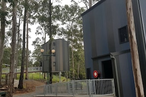 A building with a metal fence, a red circular sign, and a wooden structure with two lanterns.