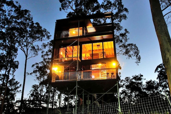 A multi-story building with balconies and large windows, surrounded by trees.