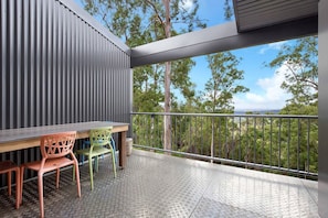 A balcony with a metal railing, a table, and two chairs.