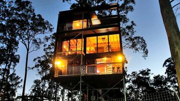 A multi-story building with balconies and large windows, surrounded by trees.