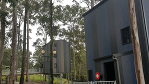 A building with a metal fence, a red circular sign, and a wooden structure with two lanterns. - Gorgeous Queensland Tree House with Great Views Perfect for Glamping, Gold Coast (Gold Coast)