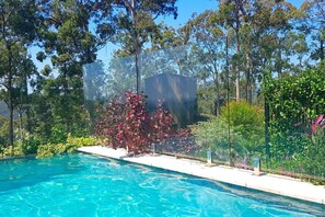 A swimming pool with clear blue water, surrounded by lush greenery and trees.