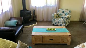Een gezellige woonkamer met een bank, een stoel, een houten salontafel en een open haard.