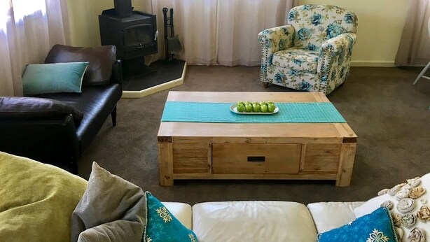 Un salon chaleureux avec un canapé, un fauteuil, une table basse en bois et une cheminée.