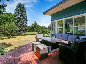 Eine Terrasse im Freien mit Esstisch und Stühlen, einer Couch und einem kleinen Tisch.