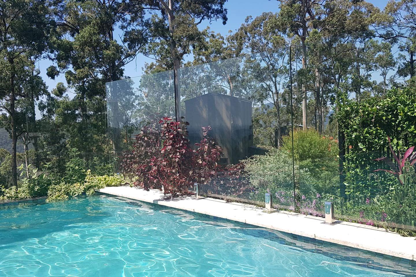 A swimming pool with clear water, surrounded by lush greenery and trees.
