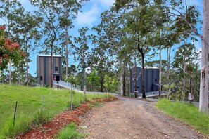 A dirt path leading to a modern building with a metal staircase and a metal fence.