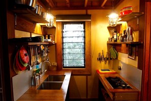 Une cuisine de taille réduite, avec des meubles en bois, une fenêtre et une cuisinière.