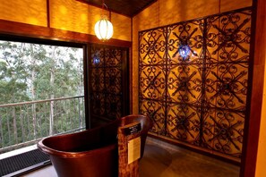 Une pièce dotée d’une grande fenêtre, d’une cloison décorative en métal, d’un seau en bois et d’un luminaire suspendu.