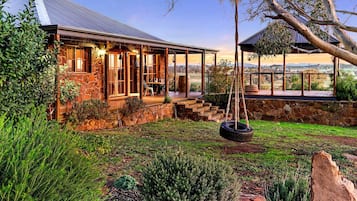 A stone house with a porch, a swing, and a view of the countryside.