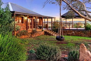 A stone house with a porch, a swing, and a view of the countryside.