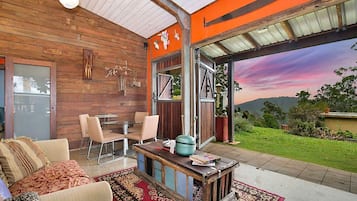 A modern interior with a wooden wall, a dining area, and a view of a sunset.