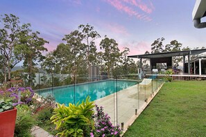 A swimming pool with a glass fence, surrounded by a grassy area and trees. - Rustic Gold Coast Cabin with Amazing Views Ideal for Glamping in Queensland (Gold Coast)
