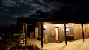A building with a covered outdoor area, a door, and a bench. - Rustic Gold Coast Cabin with Amazing Views Ideal for Glamping in Queensland (Gold Coast)
