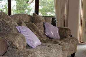 Un sofá con diseño y cojines decorativos, situado cerca de una ventana con cortinas.