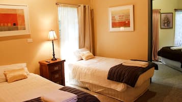 Una habitación de hotel con dos camas, una mesita de noche con lámpara, un aire acondicionado de pared y un cuadro.