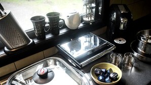 A kitchen with a coffee maker, a kettle, a toaster, a blender, and a bowl of coffee pods.