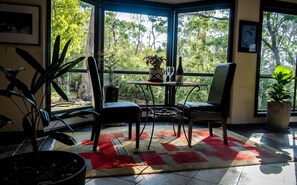 A room with a large window, a table with chairs, and a potted plant. - Marvelous Halls Gap Cabin Ideal for Romantic Getaways in Victoria (Halls Gap)
