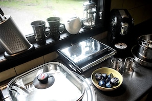 A kitchen with a coffee maker, a kettle, a toaster, a blender, and a bowl of coffee pods.