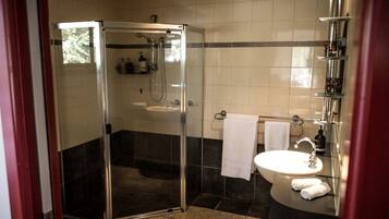 A bathroom with a glass-enclosed shower, a sink, and a mirror.