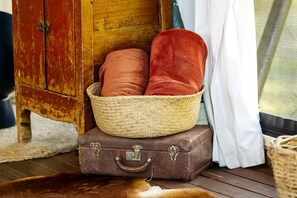 A rustic room with a woven basket on a vintage suitcase, a wooden cabinet, and a fur rug.